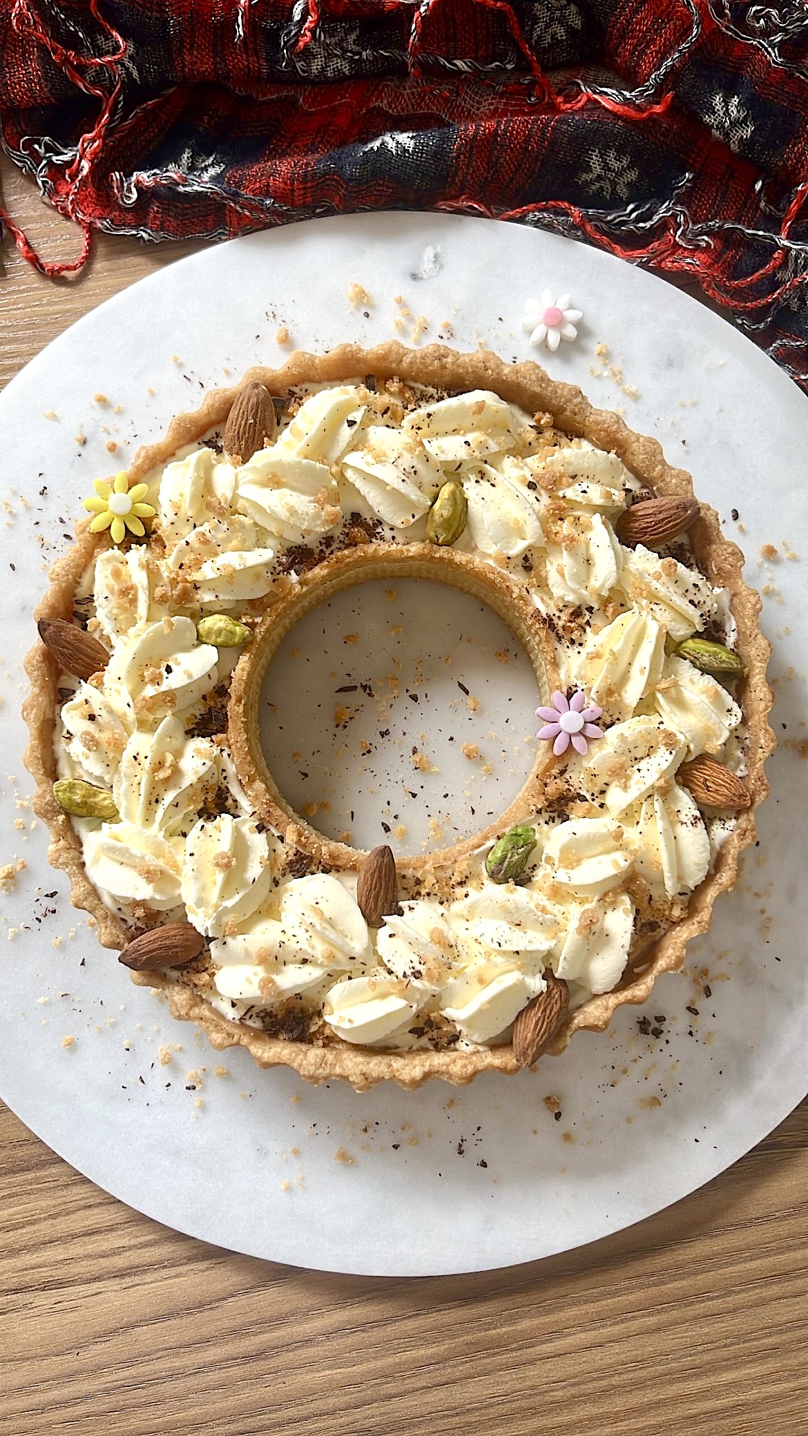 Tart ring topped with heart-shaped cream, decorated with almonds and pistachios.